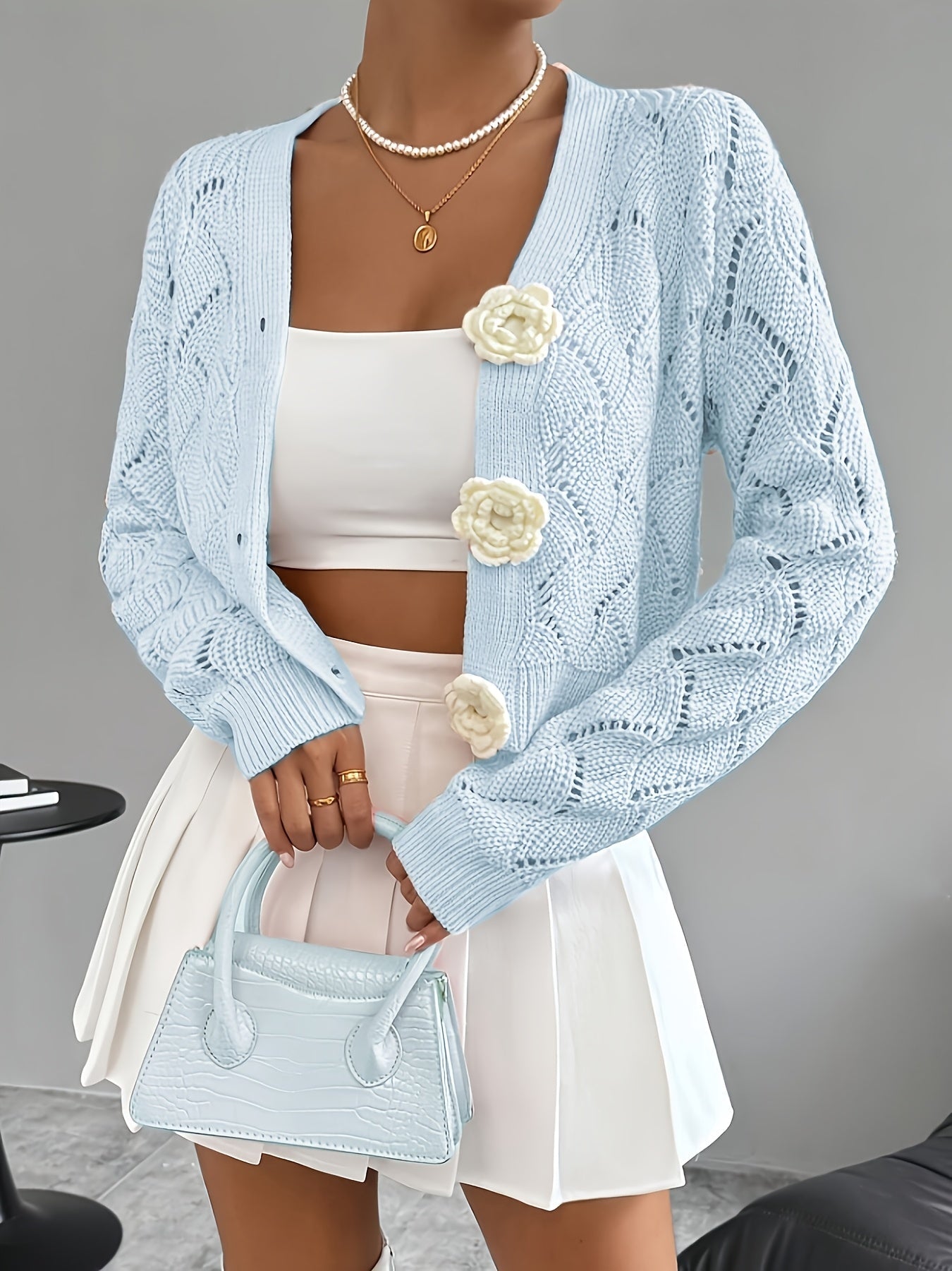 White crochet women's cardigan by Lumina Wear featuring floral button accents and elegant design.