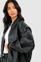 Isabella oversized black vegan leather bomber jacket with ribbed cuffs by Lumina Wear, displayed on a hanger.