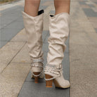 Women’s knee-high boots with studded straps, slouch design, and block heel from Lumina Wear’s Isabella collection.