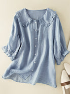 Light blue Victoria Lumina Women's relaxed fit ruffle collar top, perfect for effortless summer style, displayed on a hanger.