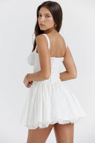 White mini dress by Lumina Vancouver featuring a lace-trimmed bodice and short sleeves, styled on a mannequin.