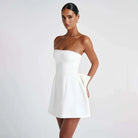 White strapless satin mini dress by Lumina Vancouver, modeled on a mannequin, showcasing elegant, fitted design.