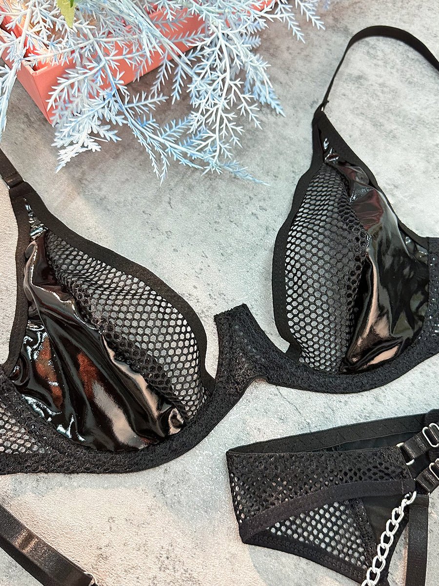 Black leather and mesh hollow lingerie set by Lumina Wear, featuring a bra, panties, and garter belt on a model.