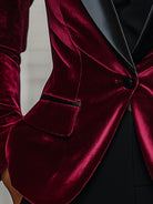 Burgundy velvet blazer by Lumina Wear with satin lapels and black rose detail, shown on a hanger.