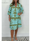 Blue and army green Bergljot spring dress by Lumina Wear featuring a flowy design and floral print, displayed on a hanger.