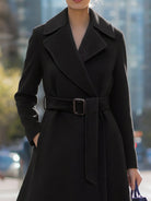 Black Lumina Vancouver Edith wool-blend midi coat with belted lapel collar, shown on a model in a stylish outdoor setting.