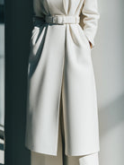 White belted minimalist wool coat by Lumina Vancouver, showing the tailored design and belt detail on a model.