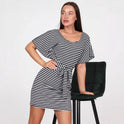 Black Elena mini dress by Lumina Wear with vertical stripes and a belt, displayed on a hanger against a white background.
