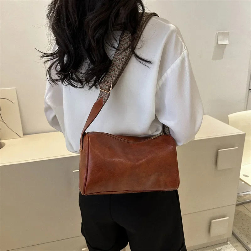 Lumina Wear Florence minimalist black crossbody handbag with patterned strap, featuring sleek design and adjustable strap length.