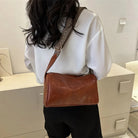 Lumina Wear Florence minimalist black crossbody handbag with patterned strap, featuring sleek design and adjustable strap length.
