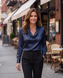 White Delphine blouse with draped fabric from Lumina Wear, shown on a hanger with soft fabric details visible.