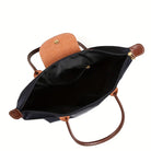 Black faux leather handbag by Lumina Wear, spacious design with chic style, featuring sturdy handles and elegant details.