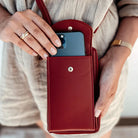 Elegant black leather clutch bag with versatile strap from Lumina Wear, featuring a sleek design and compact hand-held style.