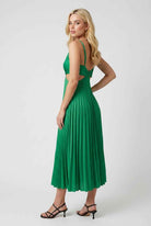 Elegant green pleated maxi dress by Lumina Wear with flowing design, showcased on a model in a natural outdoor setting.