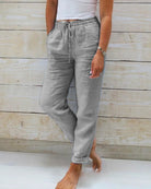 Lightweight beige linen trousers from Lumina Wear, styled for a sophisticated look, with a relaxed fit and elegant design.