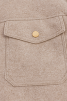 Beige Isabella Lumina Wear modern cropped zip-up jacket with pockets, displayed on a model in a casual outdoor setting.
