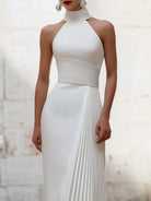 White Isabelle pleated halter-neck gown by Lumina Wear, elegant dress with flowing fabric and stylish design.