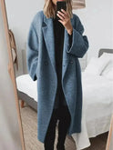 Light grey Kelly women's winter long coat by Lumina Wear, stylish and warm, shown hanging with a winter city background.