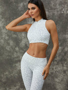 Leopard print Lumina Vancouver sports bra with zipper and stand collar, paired with white leggings, in a close-up front view.