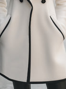 Lumina Vancouver double-breasted white coat with black trim, stylish coat for women, shown on a model.