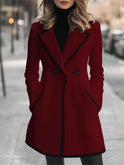 Lumina Wear double-breasted white coat with black trim, showcasing a stylish, tailored design with classic lapels and button details.