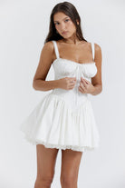 White mini dress by Lumina Vancouver featuring a lace-trimmed bodice, perfect for stylish, elegant occasions.