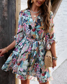 White women's floral V-neck mini dress by Lumina Vancouver, featuring a stylish and feminine design perfect for warm weather.