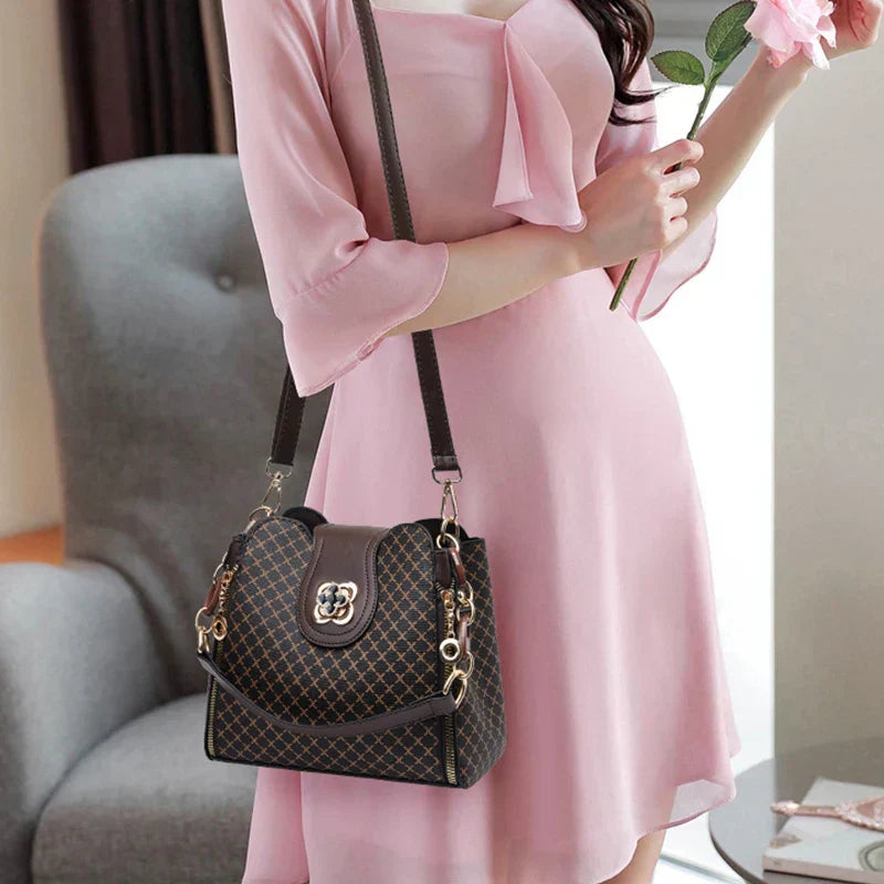 Black Marjorie quilted charm handbag with adjustable strap by Lumina Wear, featuring elegant stitching and a compact design.
