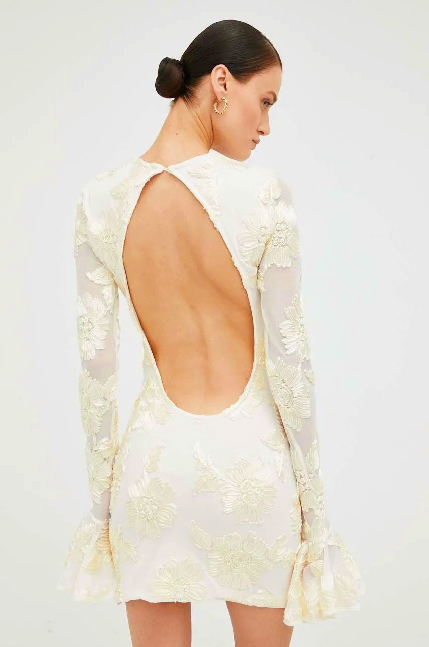 Beige Lorelei mini dress by Lumina Wear featuring open back, long sleeves, and a fitted silhouette.