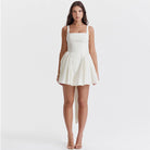White Quilla mini dress with spaghetti straps from Lumina Vancouver, shown on a mannequin, tailored for a chic, stylish look.