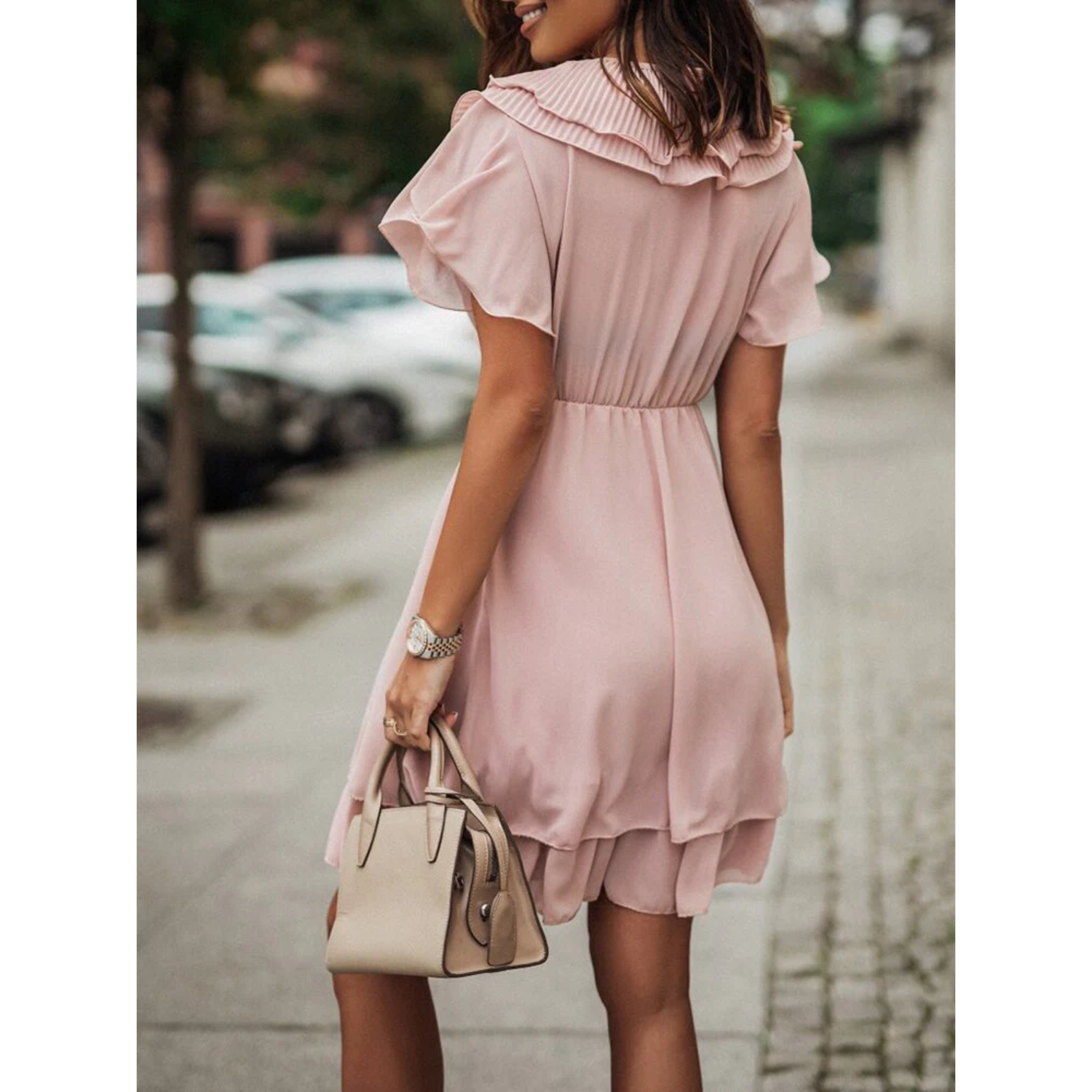 Pink Maren V-neck mini dress with a tiered design by Lumina Vancouver, showcased on a model in a stylish outdoor setting.
