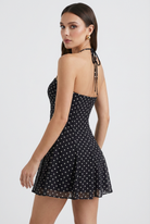 Black flared mini dress with polka dot print from Lumina Wear's Serena collection, featuring a stylish and playful design.