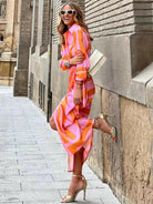 Orange and pink Solana™ printed wrap dress by Lumina Vancouver, featuring a stylish design and flowing fabric.
