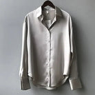 Green satin blouse by Lumina Wear featuring a classic button-down design, styled with long sleeves and elegant detailing.