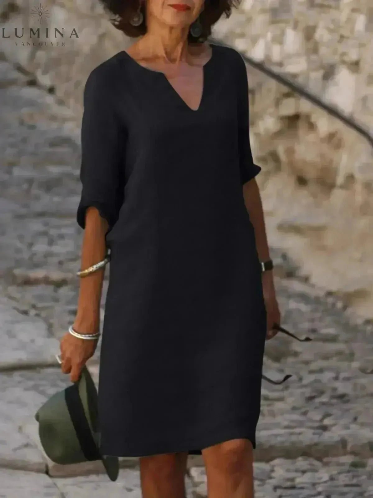 Black Suzan elegant dress with V-neckline by Lumina Vancouver, shown on a model with flowing fabric and stylish design.