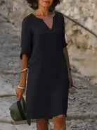 Black Suzan elegant dress with V-neckline by Lumina Vancouver, shown on a model with flowing fabric and stylish design.
