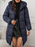 Red-brown Lumina Wear Victoria cozy longline hooded puffer coat with practical pockets, featuring a puffy insulated design and hood.