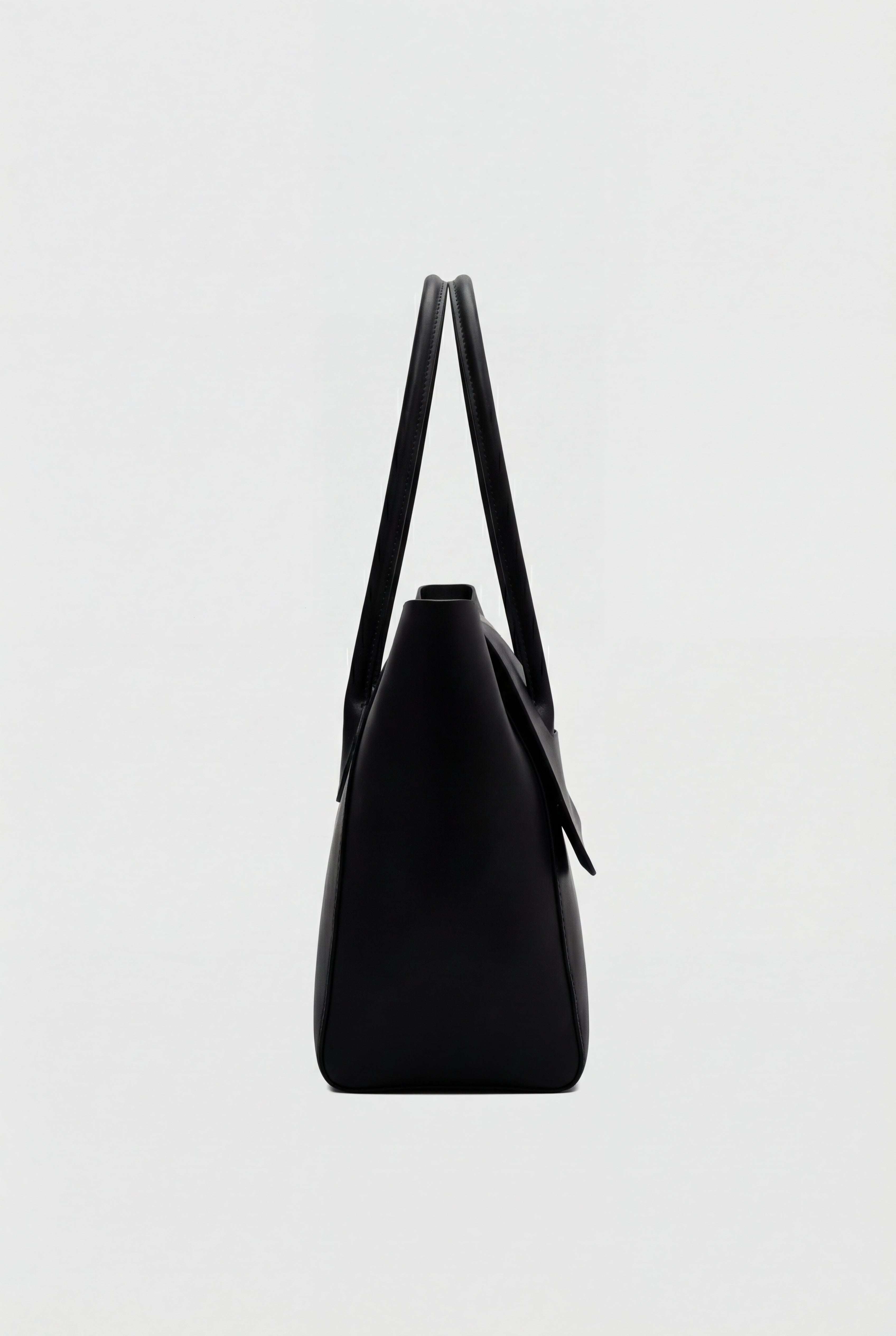 Elegant black Lumina Wear Victoria handbag with adjustable strap, featuring a sleek design and structured shape.
