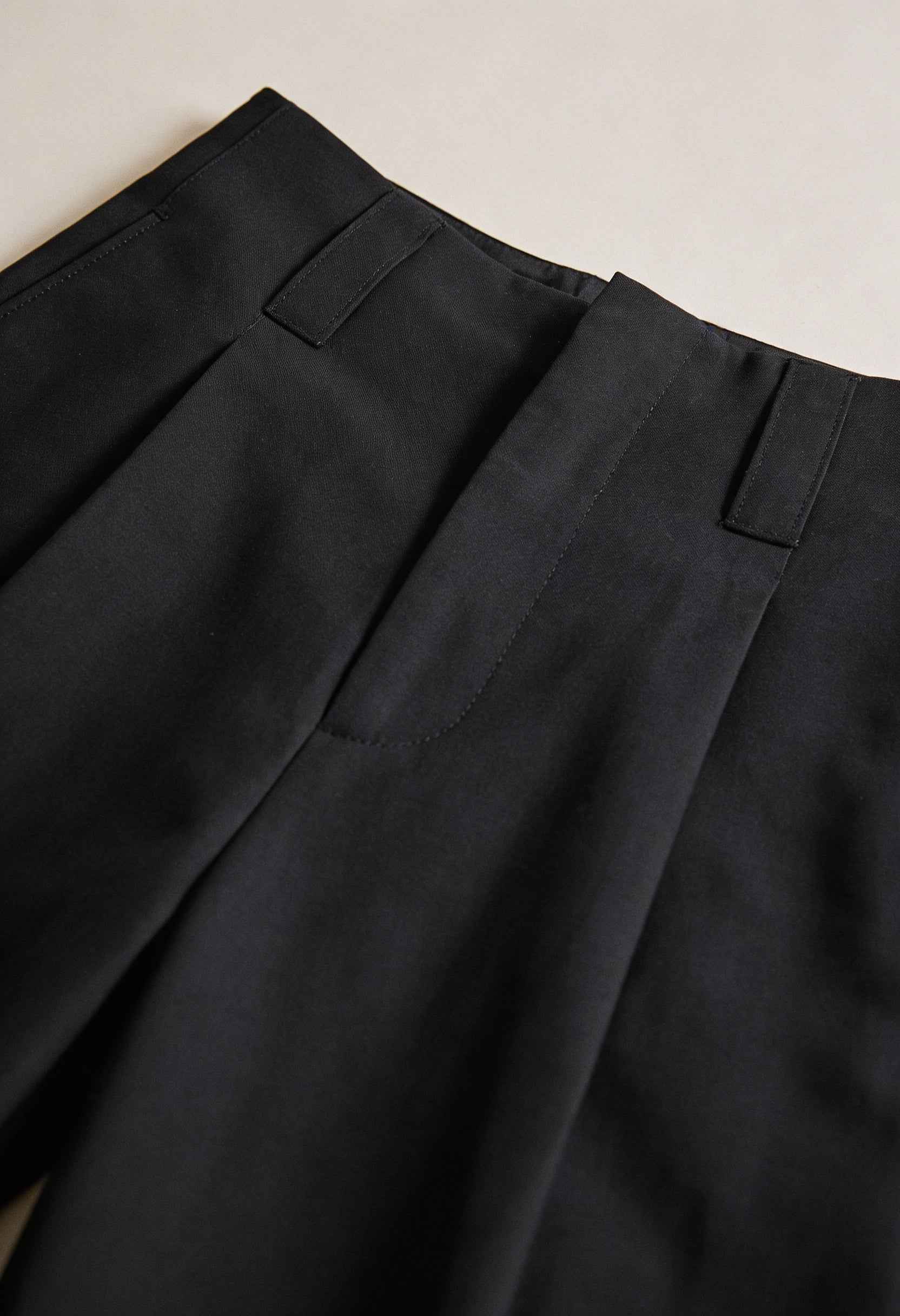 Women’s high-waisted black trousers with pleats by Lumina Wear, featuring a tailored fit and elegant style.